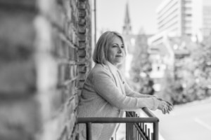 Frau blickt nachdenklich vom Balkon mit Stadtblick in Berlin.