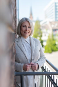 Business-Frau vor Stadt-Hintergrund, professionell und freundlich.