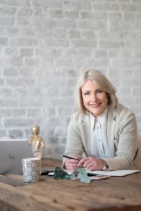 Kreative Geschäftsfrau arbeitet an einem Schreibtisch mit Laptop und Notizbuch.