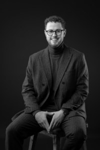 Businessportrait für Personal Branding und Karriere - photoart hübner business Hübscher Mann in Businesskleidung vor dunklem Hintergrund.