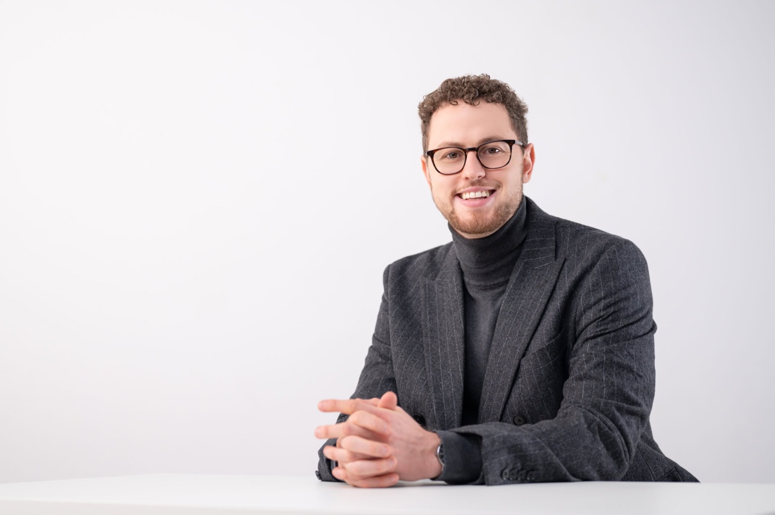 Professioneller Business-Fotograf für Unternehmensporträts bei Photoart Hübner. - photoart hübner business Business-Porträt eines Mannes in formeller Kleidung, lächelnd, vor weißem Hintergrund.