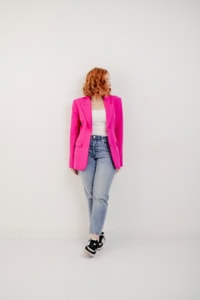 Frau in pinkem Blazer vor weißer Wand - photoart hübner business Frau in pinkem Blazer und Jeans posiert für professionelle Businessfotografie.
