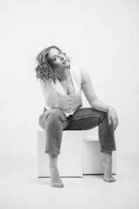 Businessfotografie Portrait Frau auf Sitz - photoart hübner business Frau sitzt auf einem weißen Block, in entspannter Pose, für professionelle Businessfotografie.