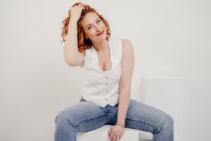 Businessfotografie Portrait einer jungen Frau mit lockigem Haar - photoart hübner business Junge Frau mit lockigem Haar in Business-Posing, lächelnd und entspannt, für professionelle Unterneh.