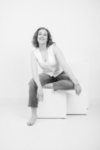 Moderne Businessfotografie für Personal Branding und Karriere - photoart hübner business Fröhliche Frau in Businesskleidung bei professionellem Fotoshooting, weißer Hintergrund.