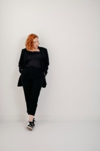 Businessfotografie Portrait einer jungen Frau in Businesskleidung - photoart hübner business Frau in Businessoutfit vor weißer Wand, professionell und selbstbewusst.