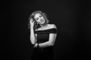 Businessporträt Frau mit lockigem Haar vor schwarzem Hintergrund - photoart hübner business Frau mit lockigem Haar posiert für professionelle Businessfotografie, ideal für Personal Branding un.