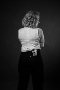 Frau mit lockigem Haar blickt nach rechts - photoart hübner business Frau in Businesskleidung, seitlich fotografiert, mit professionellem Look.