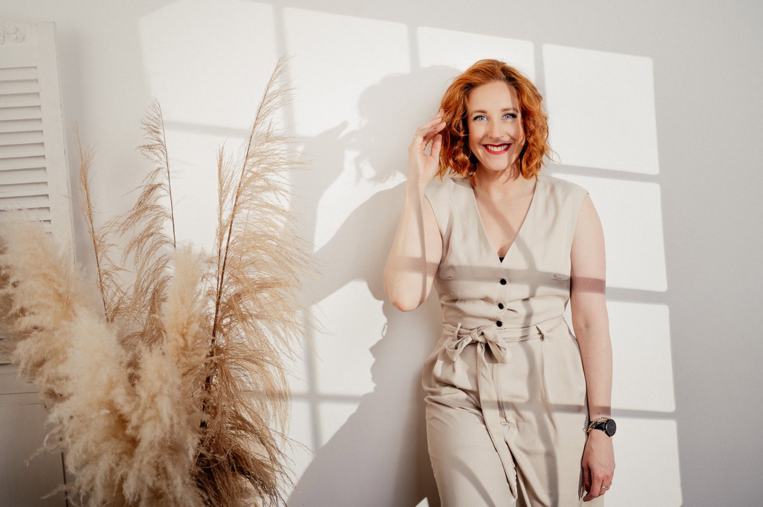 Moderne Frau in hellen Outfits vor Fenster mit Schattenwurf - photoart hübner business Fröhliche Frau in hellen Outfits vor Fenster mit Schattenwurf.