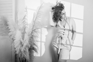 Businessfotografie für Selbstständige und Unternehmen - photoart hübner business Frau in Businesskleidung posiert vor Fenster mit Schattenwurf, professionelles Businessfoto.