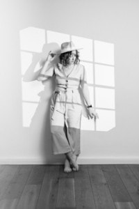 Businessfotografie Portrait mit natürlichem Licht und kreativer Schattenwirkung - photoart hübner business Porträt einer Frau in Businesskleidung, die an einer Wand mit Schattenmuster steht, ideal für Person.