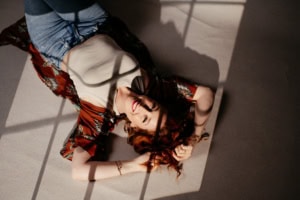 Businessfotografie Portrait mit natürlichem Licht und kreativer Beleuchtung - photoart hübner business Porträt einer jungen Frau mit roten Haaren, liegend auf dem Boden, in einem professionellen Fotoshoo.