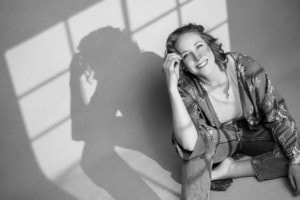 Moderne Portraitfotografie für Business und Persönlichkeit - photoart hübner business Professionelles Business-Portrait einer lachenden Frau vor Fenster mit Schatteneffekt.