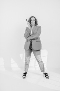 Businessfotografie Frau mit Smartphone und Krawatte - photoart hübner business Frau in Businessoutfit mit Smartphone, lächelnd, im Studio fotografiert.