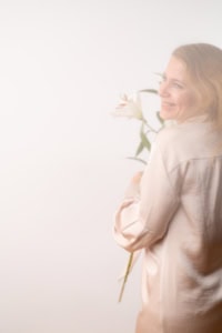 Businessfotografie mit Blumen und natürlichem Licht - photoart hübner business Frau hält weiße Blume bei Business- und Personal Branding Fotoshoot.